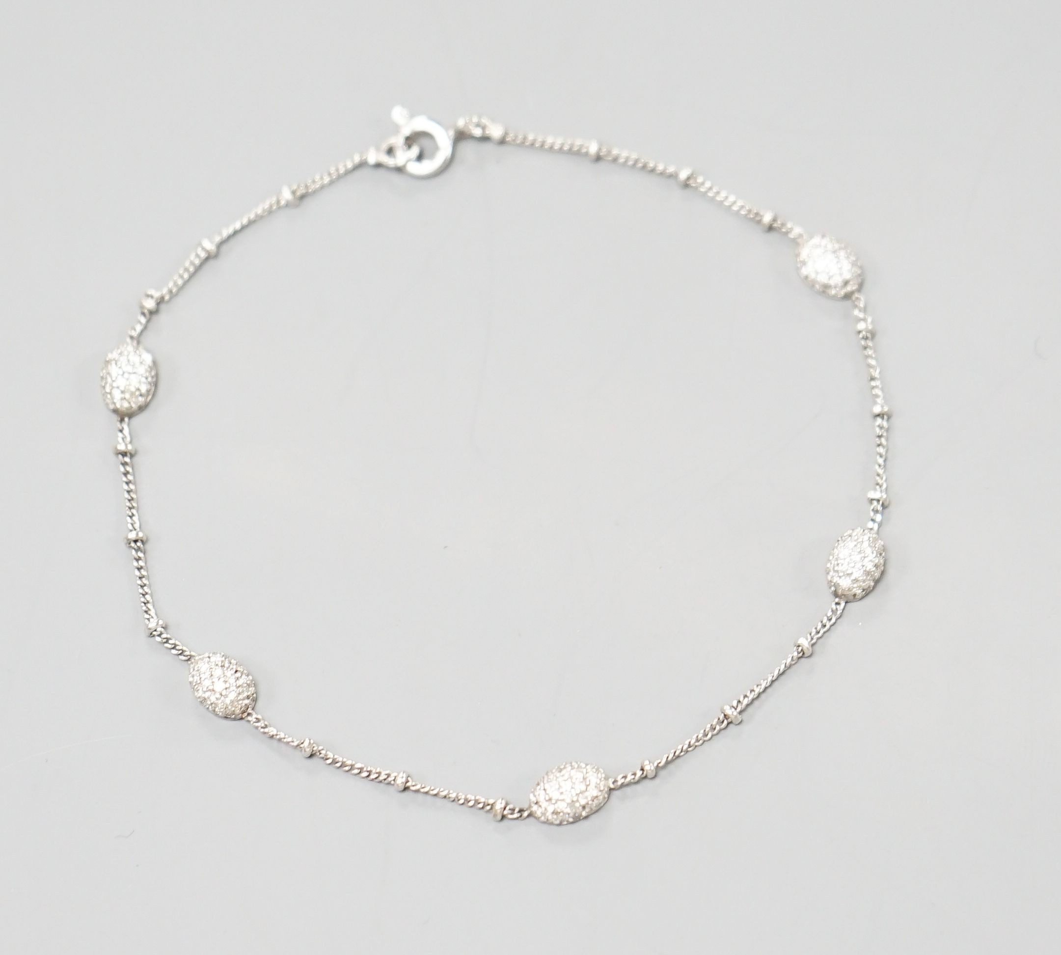 A modern 750 white metal and diamond chip set demi lune link bracelet, 19cm